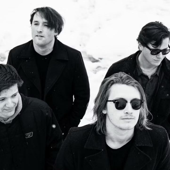 The four members of Bleu Grave in black coats, standing in snow.